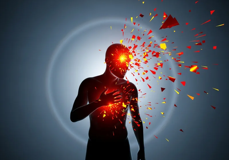 Ciało człowieka rozpadające się w wybuchu czerwonych i żółtych cząstek na tle przygaszonej poświaty.